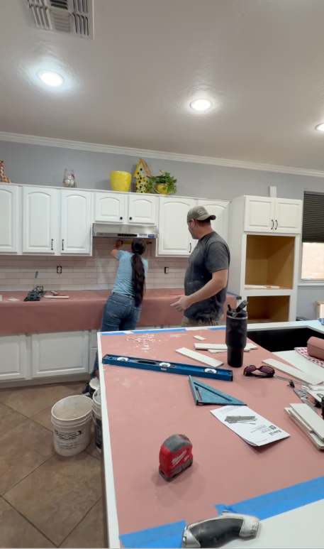 Laura and Travis both working — Laura drilling, Travis holding materials